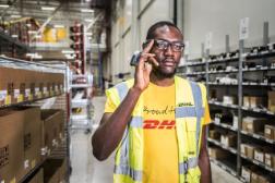 A DHL employee on his way to pick a package inside a warehouse.