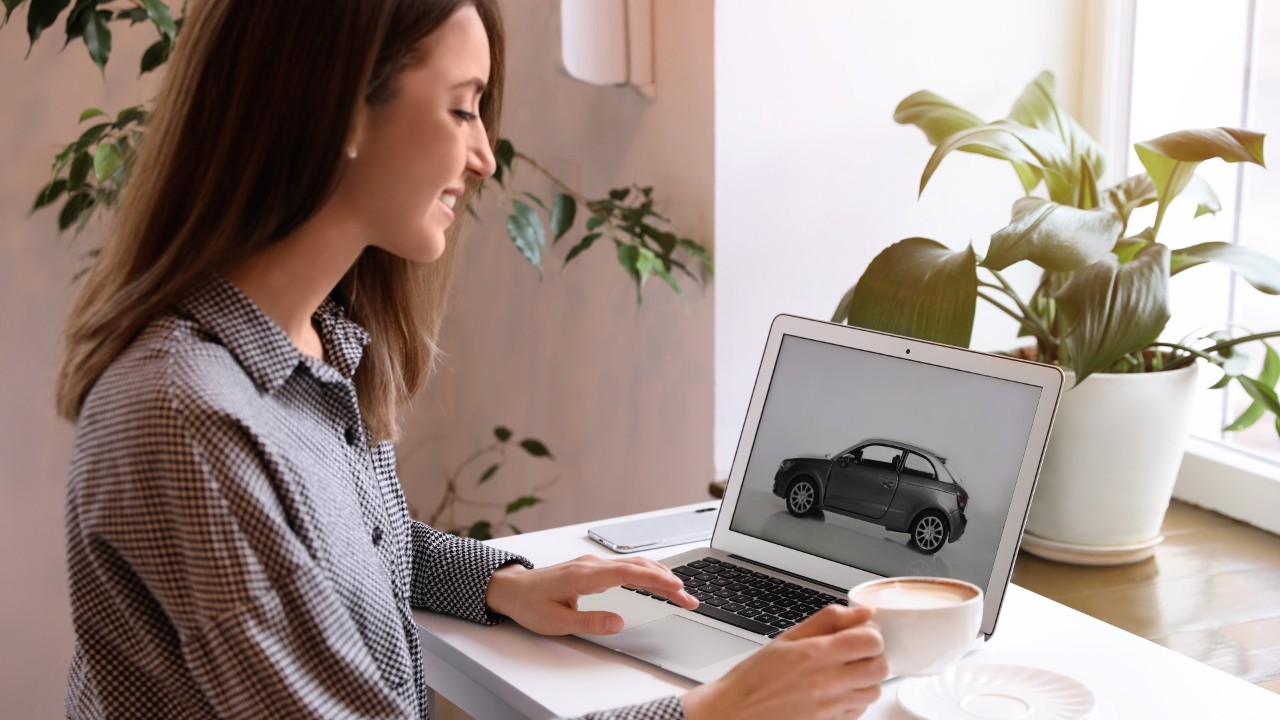 Dame die een auto op een laptop bekijkt