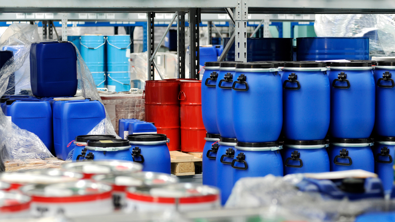 Middle-aged man wearing plaid shirt smiles sitting at his computer in a large room