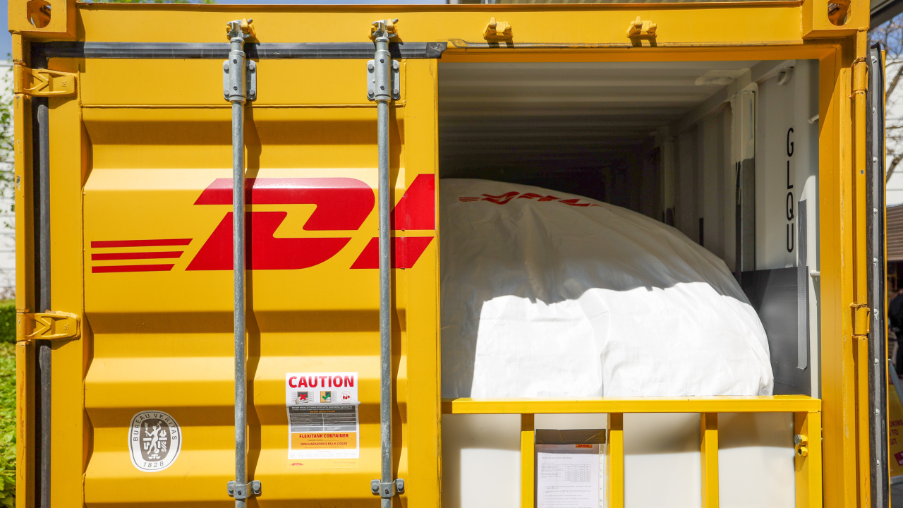Middle-aged man wearing plaid shirt smiles sitting at his computer in a large room